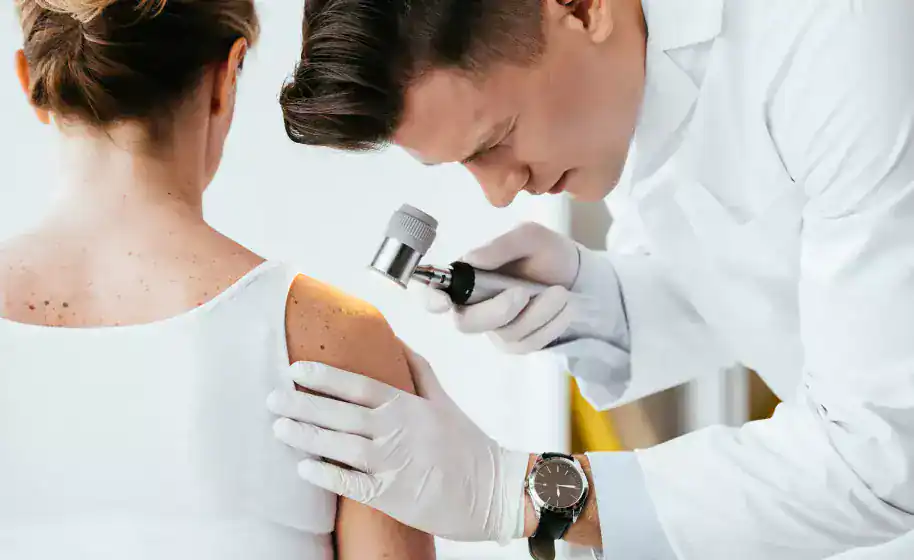 Doctor examining patient's skin with a dermatoscope in a clinical setting.