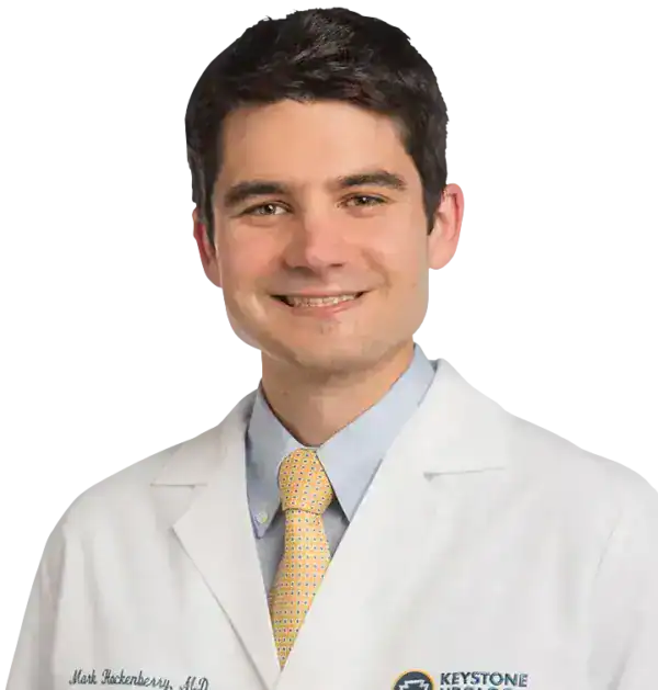Medical professional in white coat with Keystone logo, smiling confidently.