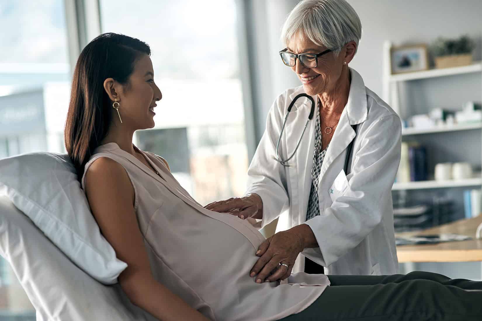 Doctor examining pregnant woman in a clinical setting.