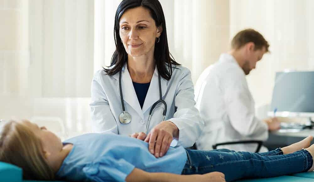 Doctor examining a young girl in a medical clinic setting.