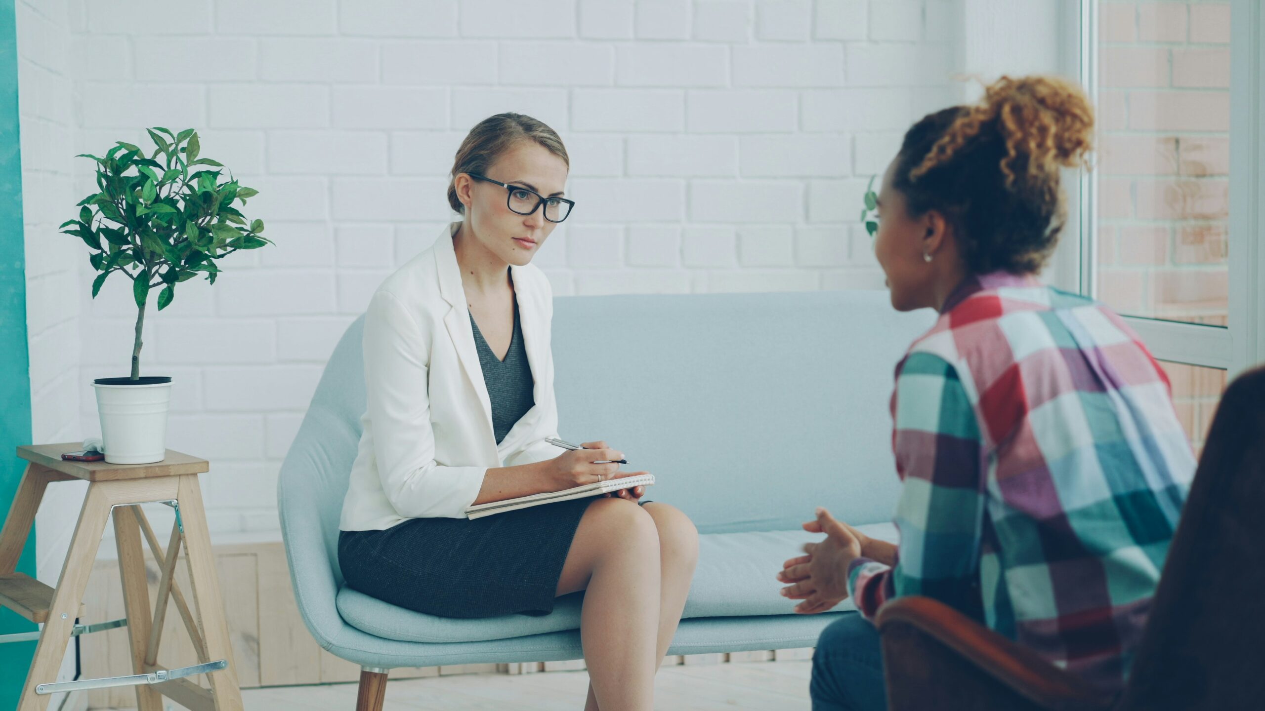 Therapist taking notes during a counseling session with client
